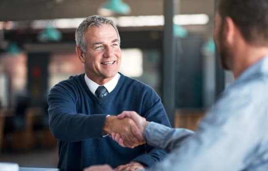 Two professionals shaking hands in an office, indicating a successful agreement