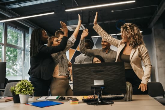 Team of diverse professionals celebrating success together in an office environment